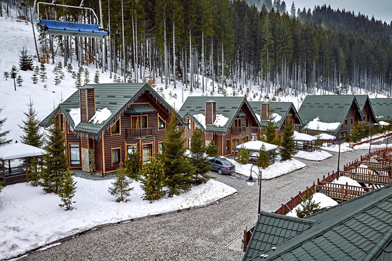 winter-vacation-holiday-wooden-house-mountains-covered-with-snow-blue-sky-skis-front-house_639032-857 1